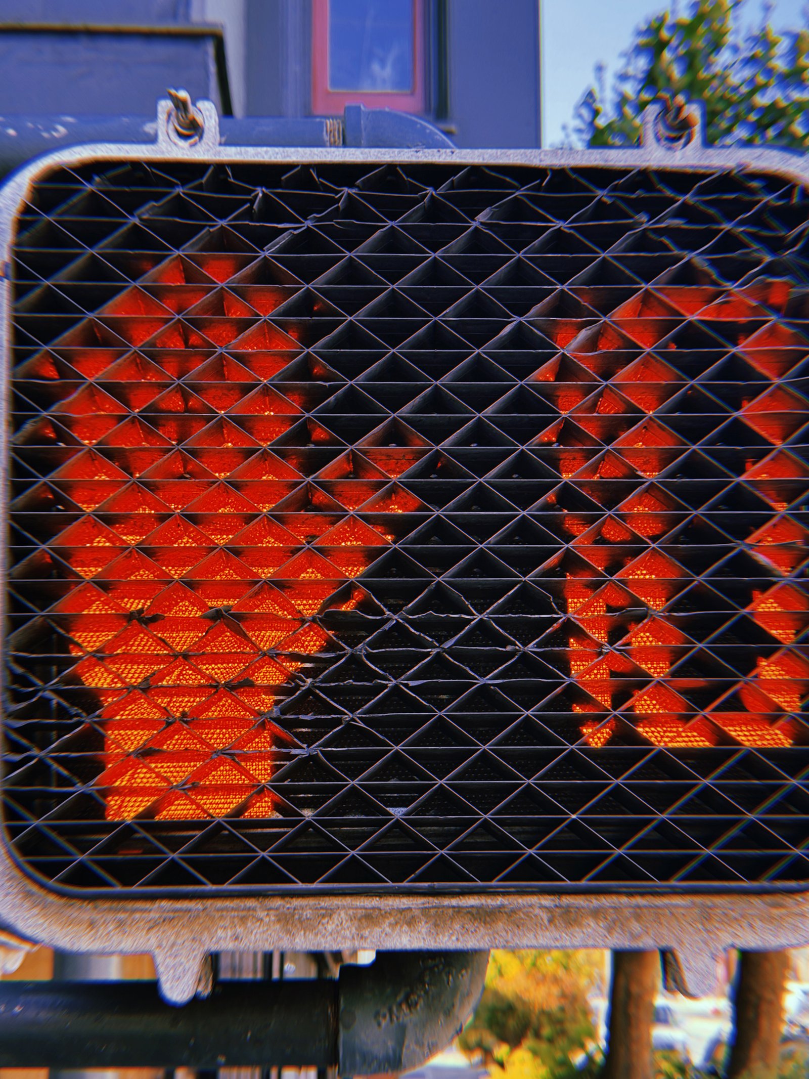 Red pedestrian countdown number 1 illuminated behind a black triangular protective grid, with the signal housing and mounting structure visible.