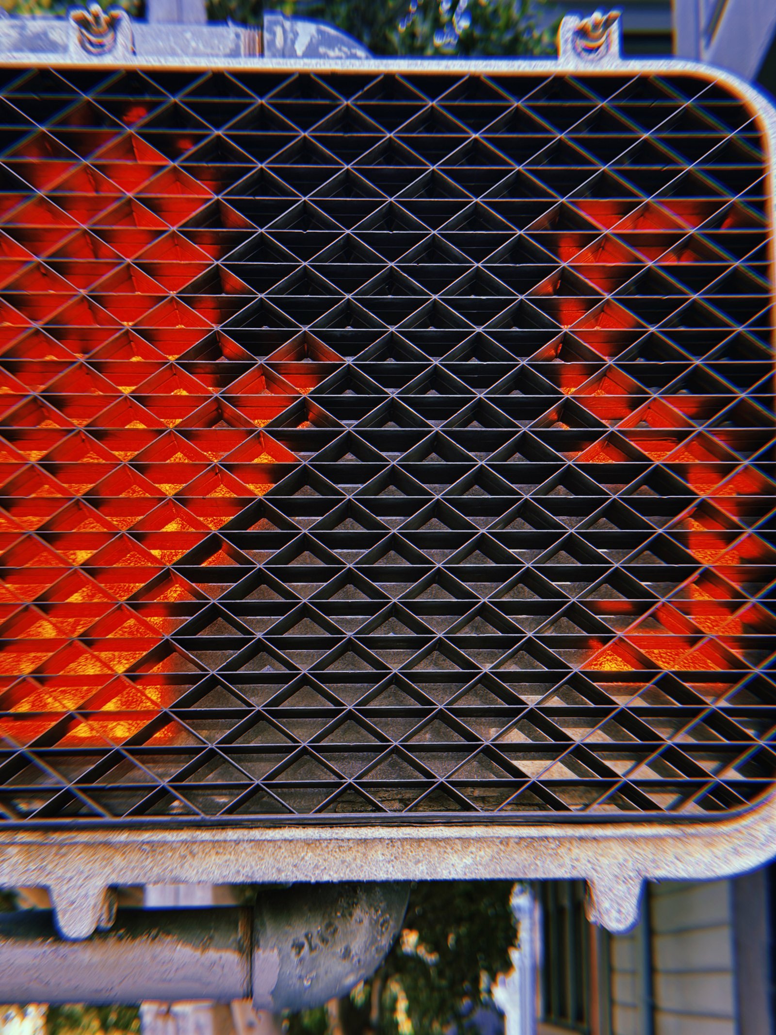 Red pedestrian countdown number 2 illuminated behind a black triangular protective grid, with the signal housing and metal mounting pipe visible.